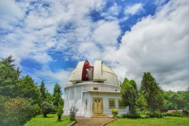 Observatorium Bosscha, 1. Mari mulai dari atraksi wisata populer di Bandung yang bisa kalian jajal dengan harga minimalis, bahkan ada yang gratis lho! Misalnya saja aneka taman tematiknya yang keren, 2. Dengan 10 ribu rupiah, kalian bisa mengelilingi kota Bandung sambil bergaya keren di atas Bus Bandros, 3. Salurkan hasratmu jadi koboi dengan naik kuda. Harganya mulai dari 5 ribuan saja lho, 4. Ingin tahu seperti apa suasana pasar terapung? Nggak usah jauh-jauh ke Thailand karena di Bandung pun ada Floating Market, 5. Terkadang, wisata murah bisa begitu dekat dengan bintang. Nggak percaya? Mampir saja ke Observatorium Bosscha yang ada di bilangan Lembang untuk membuktikannya, 6. Walau bukan obyek wisata mayor, Cagar Alam Junghuhn layak untuk dikunjungi oleh kalian yang menghargai jasa para pahlawan, 7. Air terjun Maribaya selalu menjadi favorit bagi mereka yang mencintai suasana alam dengan budget yang ekonomis, 8. Dan, dari Maribaya, kalian bisa langsung menuju Taman Hutan Raya Juanda. Harga tiketnya sama ekonomisnya lho, 9. Untuk melengkapi kunjungan di Taman Hutan Raya Juanda, sekalian saja mampir ke tempat selfie paling populer di Bandung, yaitu Tebing Keraton, 10. Menikmati sejuknya udara Bandung bisa kalian lakukan sambil mengenal ragam fauna di Kebun Binatang Bandung, 11. Area Bandung Selatan juga punya banyak obyek wisata yang menyayangi kantong kalian. Misalnya saja wisata Kawah Putih-nya yang super populer itu, 12. Untuk kalian para pecinta wisata alam dan pengagum nilai-nilai romantisme, Situ Patenggang menjadi tempat yang wajib kalian sambangi di Bandung, 13. Mampirlah ke Pemandian Air Panas Cibolang yang akan menghangatkan tubuh kalian dari gigitan udara dingin di Ciwidey, 14. Cibolang bukan satu-satunya tempat yang dapat menghangatkan tubuh kalian saat dingin. Kunjungi saja Taman Wisata Alam Cimanggu yang juga menawarkan kolam pemandian air panas alami, 15. Atau, mampirlah ke pemandian Air Panas Alami Walini/Rancawalini juga populer di wilayah Ciwidey. Kalian dapat menikmati suasana berendam air panas di tengah perkebunan teh, 16. Wisata di Ciwidey akan semakin lengkap jika kalian berjalan-jalan di tengah Perkebunan Teh Rancabali. Pemandangannya yang indah akan membuat siapapun mendadak suka mengambil foto, 17. Untuk menutup wisata hemat di Bandung, mampirlah ke Pasar Gedebage untuk belanja pakaian second berkualitas bagus. Harganya? Murah meriah!, 18. Balitsa Lembang yang Instagramable, 19. Keindahan Babakan Siliwangi yang bikin mata terpana, 20. Mengintip Dinosaurus di Museum Geologi, 21. Kawah Rengganis yang begitu eksotis, 22. Epic Sunrise di Venue Gantole Cililin, 23. Menikmati pesona alam hijau di Bukit Teletubies, 24. Menikmati pesona alam hijau khas bebukitan di Bukit Jamur, 25. Pesona Curug Bellarosa yang bikin pikiran adem, 26. Epiknya pemandangan di Gunung Nini Pangalengan