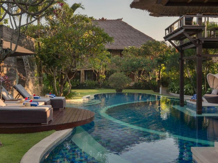 Kolam renang dan tempat berjemur dengan latar belakang villa asta