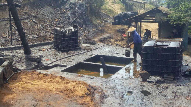 Penambang sedang mengangkat minyak mentah ke tanki minyak di Desa Wonocolo.