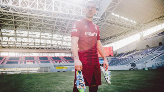Lukas Podolski saat memegang sepatu bercorak Captain Tsubasa