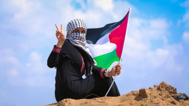 Seorang wanita mengibarkan bendera Palestina di Jalur Gaza.