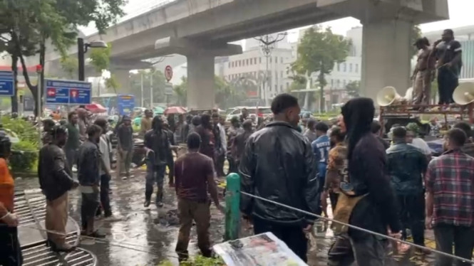 Puluhan massa aksi yang bertahan ditengah hujan deras di depan Kantor Kementerian HAM RI