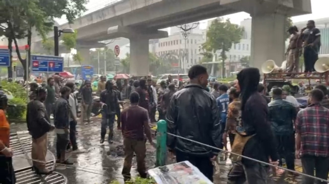 Puluhan massa aksi yang bertahan ditengah hujan deras di depan Kantor Kementerian HAM RI