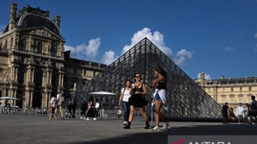 Pengunjung melintasi Piramida Louvre yang diarsiteki I M Pei di Museum Louvre