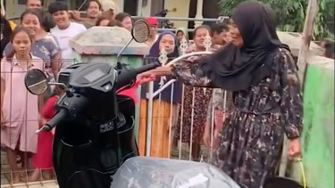 Warga menyiram motor baru yang baru dibeli dengan air kembang