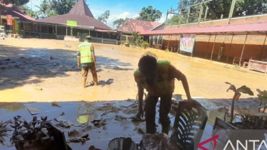 Warga membersihkan tumpukan material imbas banjir yang melanda Kota Padang