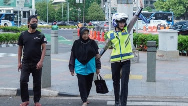 Ilustrasi polisi lalu lintas (polantas) membantu masyarakat menyebrang jalan