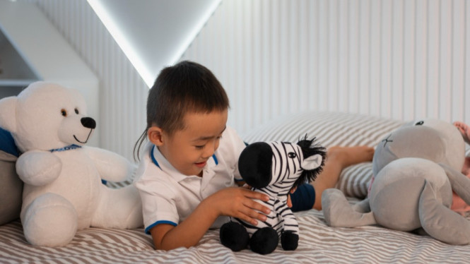 Ilustrasi anak laki-laki main boneka, Mitos 1: Semua Anak Harus Berjalan atau Berbicara pada Usia Tertentu, Mitos 2: Anak yang Tidak Membaca Sebelum Sekolah Akan Tertinggal, Mitos 3: Anak yang Pemalu atau Pendiam Memiliki Masalah Sosial, Mitos 4: Semua Anak Harus Makan Banyak untuk Tumbuh Sehat, Mitos 5: Mainan Edukatif Mahal Diperlukan untuk Perkembangan Otak