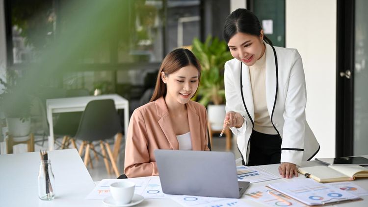 Two beautiful young Asian businesswomen working together in the office&period; Professional Asian female boss training and coaching her assistant&period;