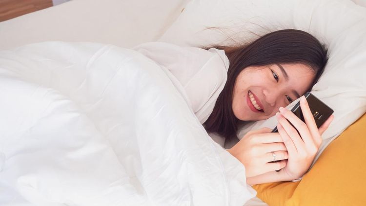 asian girl wake up on bed and playing with the mobile phone, 1. Otak kewalahan sejak pagi hari, 2. Siklus tidur berantakan, 3. Membuat mood dan emosi jadi tidak enak, 4. Gangguan pada fokus dan produktivitas, 5. Dapat menimbulkan mata lelah, 1. Nyalakan fitur mode pesawat sebelum tidur, 2. Gunakan alarm dengan jam weker daripada HP, 3. Menghapus aplikasi media sosial sementara, 4. Buat rutinitas pagi yang sehat, 5. Melakukan meditasi di pagi hari