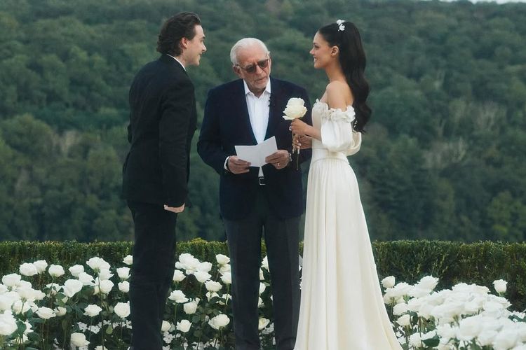 Brooklyn Beckham, Nicola Peltz, nicola peltz gaun vintage, 7 Detail Gaya Nicola Peltz Saat Pembaruan Janji Nikah, Pakai Gaun 1980-an Milik Ibu, 1. Gaun off-the-shoulder, 2. Body korset yang anggun, 3. Rok panjang jatuh natural, 4. Detail bunga pada lengan, 5. Tatanan rambut dan makeup, 6. Aksesori sederhana namun elegan, 7. Busana Brooklyn Beckham