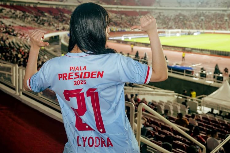 Lyodra Ginting, Piala Presiden 2025, penampilan lyodra di piala presiden 2025, gaya Lyodra di Piala Presiden 2025, Lyodra Padukan Jersey dan Rok Ruffle di Piala Presiden 2025, Intip Detail Outfitnya, 1. Jersey Biru, 2. Mini skirt ruffle putih, 3. Obi etnik merah, 4. Boots, 5. Rambut wavy tergerai, 6. Makeup flawless