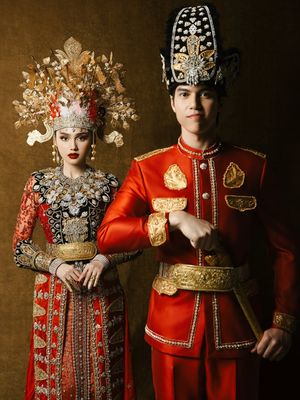 7 Detail Busana Adat Gorontalo Syifa Hadju dan El Rumi saat Prewedding, Serba Merah, 1. Dominasi warna merah yang menjadi pusat perhatian, 2. Mahkota tinggi dengan ornamen emas pada busana Syifa, 3. Detail payet penuh di bagian dada dan bahu, 4. Lengan transparan dengan payet merah, 5. Sabuk emas lebar sebagai penegas siluet, 6. Busana El Rumi bergaya formal dengan aksen emas, 7. Perpaduan keseluruhan tampak serasi dan berkarakter