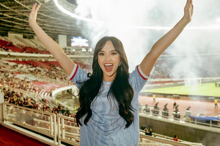 Lyodra Ginting, Piala Presiden 2025, penampilan lyodra di piala presiden 2025, gaya Lyodra di Piala Presiden 2025, Lyodra Padukan Jersey dan Rok Ruffle di Piala Presiden 2025, Intip Detail Outfitnya, 1. Jersey Biru, 2. Mini skirt ruffle putih, 3. Obi etnik merah, 4. Boots, 5. Rambut wavy tergerai, 6. Makeup flawless