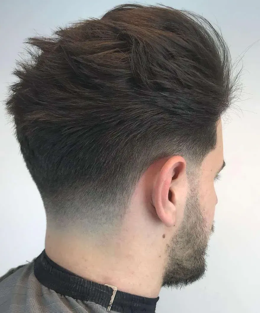1. High and Tight Haircut, 2. Two Block, 3. Slicked-back Undercut, 4. Comma Hair, 5. Taper Fade, 6. Fluffy Hair, 7. Curtain Haircut / Curtain Bangs, 8. Mullet Hair, 9. Mandarin Haircut, 10. Buzz Cut, 11. Medium Length Haircut, 12. French Crop, 13. Layered Bowl Cut, 14. Ivy League Cut, 15. Pompadour Hairstyle