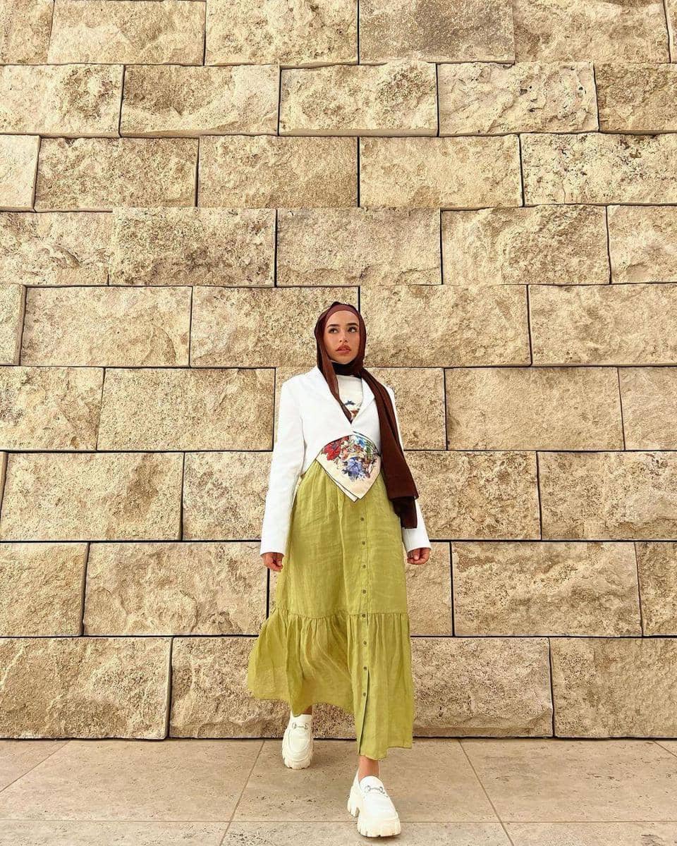 instagram.com/bazzibatul, 1. Gaya hijab yang beda dari biasanya, coba tumpuk scarf top dan cropped blazer serba putih. Berikan sentuhan warna dengan lime green skirt dan hijab warna cokelat., 2. Tampil dreamy dengan OOTD bernuansa warna biru. Padu-padankan cardigan, shoulder bag, dan sneakers serba warna biru. Cukup pasangkan dengan celana jeans yang simpel., 3. Ciptakan outfit hijab yang keren dengan kombinasi kemeja, coat hijau, dan trousers. Makin kece jika dilengkapi dengan aksesori sunnies dan combat boots., 4. Gaya kasual yang manis, andalkan perpaduan tie-dye shirt dan floral skirt. Nggak ketinggalan sepatu boots dan hijab berwarna senada., 5. Kalau untuk gaya formal, kenakan blazer set warna hijau sage untuk tampil chic. Sempurnakan dengan hijab dan sling bag berwarna netral.