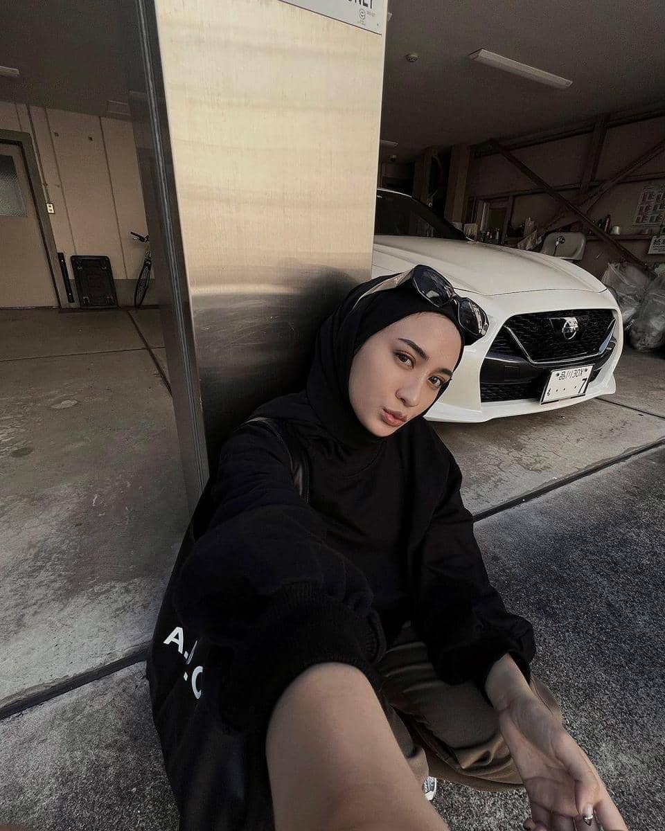 instagram.com/helminursifah, 1. Gaya selfie kekinian di dalam mobil, coba arahkan wajah ke depan kamera dengan menundukkan sedikit kepalamu. Ini bisa jadi trik agar wajah nggak terlihat bulat saat memakai hijab., 2. Tampil playful dengan kolase foto selfie menggunakan timer. Ambil bangku dan berpose sambil duduk, lalu tunjukkan ekspresi terbaikmu., 3. Trik selfie yang lagi tren, gunakan kamera belakang dan atur pakai wide lens atau mode 0,5x. Cara ini bisa jadi andalan buat kamu yang nggak suka foto selfie yang terlalu nge-zoom., 4. Kalau ingin sekalian menampilkan OOTD modismu, foto mirror-selfie jawabannya. Arahkan kamera ke depan cermin untuk berpose dengan full-body., 5. Buat kamu yang masih kaku foto sendiri, selfie bersama teman atau keluarga terkasih juga nggak masalah. Foto selfie pun dijamin kelihatan lebih natural.
