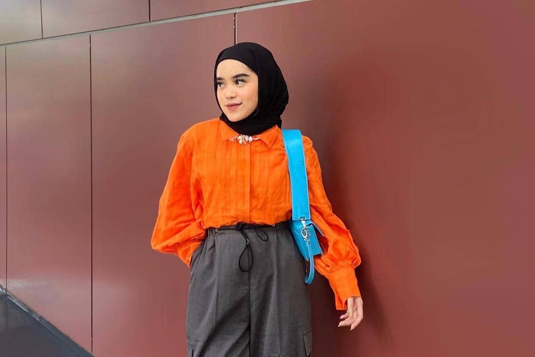instagram.com/raihanand, 1. Coat bernuansa oranye cocok dipasangkan dengan outfit serba netral. Kombinasi crewneck dan hijab warna cokelat bisa jadi andalan., 2. Jangan ragu memadukan tie-waist dress oranye dengan warna mencolok lainnya. Pilih hijab dan shoulder bag serba warna electric blue yang kece., 3. Hijab putih memang cocok dipasangkan dengan warna apa pun, termasuk sweater oranye. Makin modis pakai white quilted vest sebagai pelengkap., 4. Selain putih, hijab hitam juga nggak pernah gagal untuk outfit apa pun. Kenakan kemeja oranye dan bawahan cargo pants, lengkap dengan square-toe heels yang kekinian., 5. Padu-padan blus dan wide pants serba oranye tampak senada dengan hijab krem yang simpel. Tambahkan pink belt untuk mempermanis penampilan.