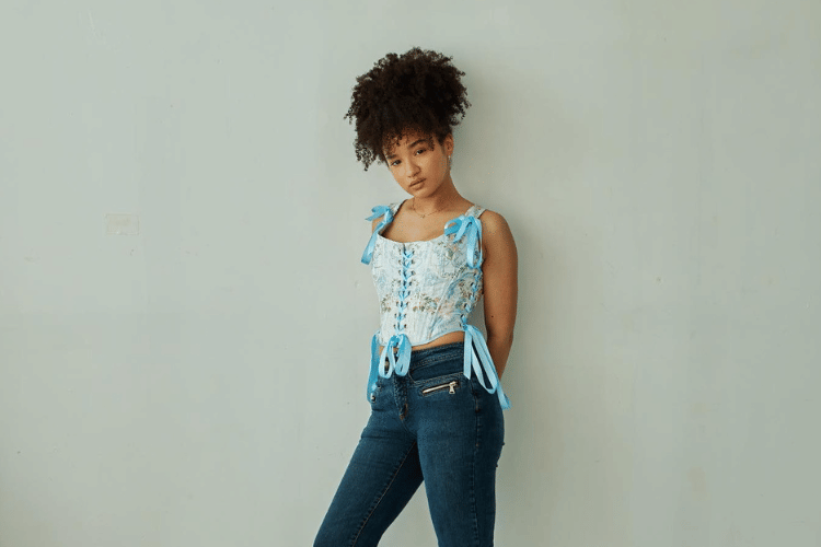 COVER STORY FOR POPBELA ARTICLE (23).png, 1. Bergaya Y2K dengan baby tees putih polos, Eve Edwards kombinasikan bersama celana denim semi flare plus chunky belt dan sandal Crocs bersol tebal. , 2. Pakai kemeja lengan panjang dengan tambahan korset, Eve Edwards sempurnakan look terbaiknya ini bersama celana cargo hijau army dan sneakers kesayangan. , 3. Hangout saat libur syuting, Eve Edwards tetap modis dengan padu-padan turtleneck rajut model crop top, hotpants hitam, knee boots senada serta bandana putih sebagai aksesori kepala., 4. Pemotretan simpel dengan atasan korset biru langit, Eve Edwards pilih celana panjang denim gelap dan sepatu boot koboi untuk melengkapi penampilannya., 5. Pose bersama Anwen O'Driscoll pemeran karakter Riri, Eve Edwards tampil chic dalam balutan gaun halter hitam ketika promosi serial Netflix Bet di Casa Loma, Kanada.