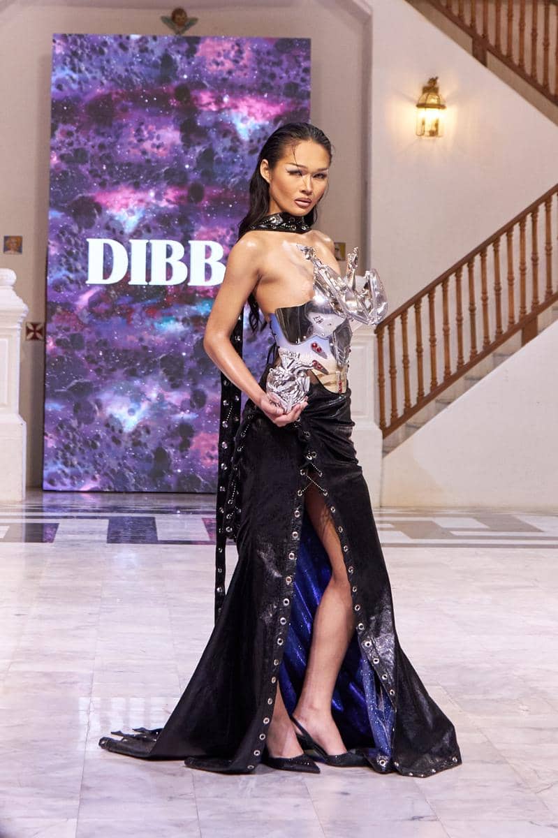 DIBBA - Fall Winter 2025 - Runway - Thailand Fashion Week - 20.jpg, 1. Berinovasi pada material, Odyssey memperkenalkan tekstil inovatif seperti printed crystal mesh & kain aktif termal yang diyakini akan hits di 2026, 2. Material dinamis ini tidak hanya menantang desain konvensional, tetapi menegaskan pendekatan avant-garde DIBBA terhadap fungsionalitas & tekstur, 3. Setiap karya dalam koleksi ini berperan sebagai bab dalam narasi kosmik, yang mengubah model menjadi pengelana dalam lanskap mimpi futuristik, 4. Odyssey dari DIBBA membayangkan kembali fashion sebagai wahana penemuan, tempat gaya bertemu hal-hal yang belum dikenal melalui imajinasi, 5. Presentasi ini menegaskan pengaruh global DIBBA dengan narasi lintas budaya dan semangat eksperimental untuk audiens dunia