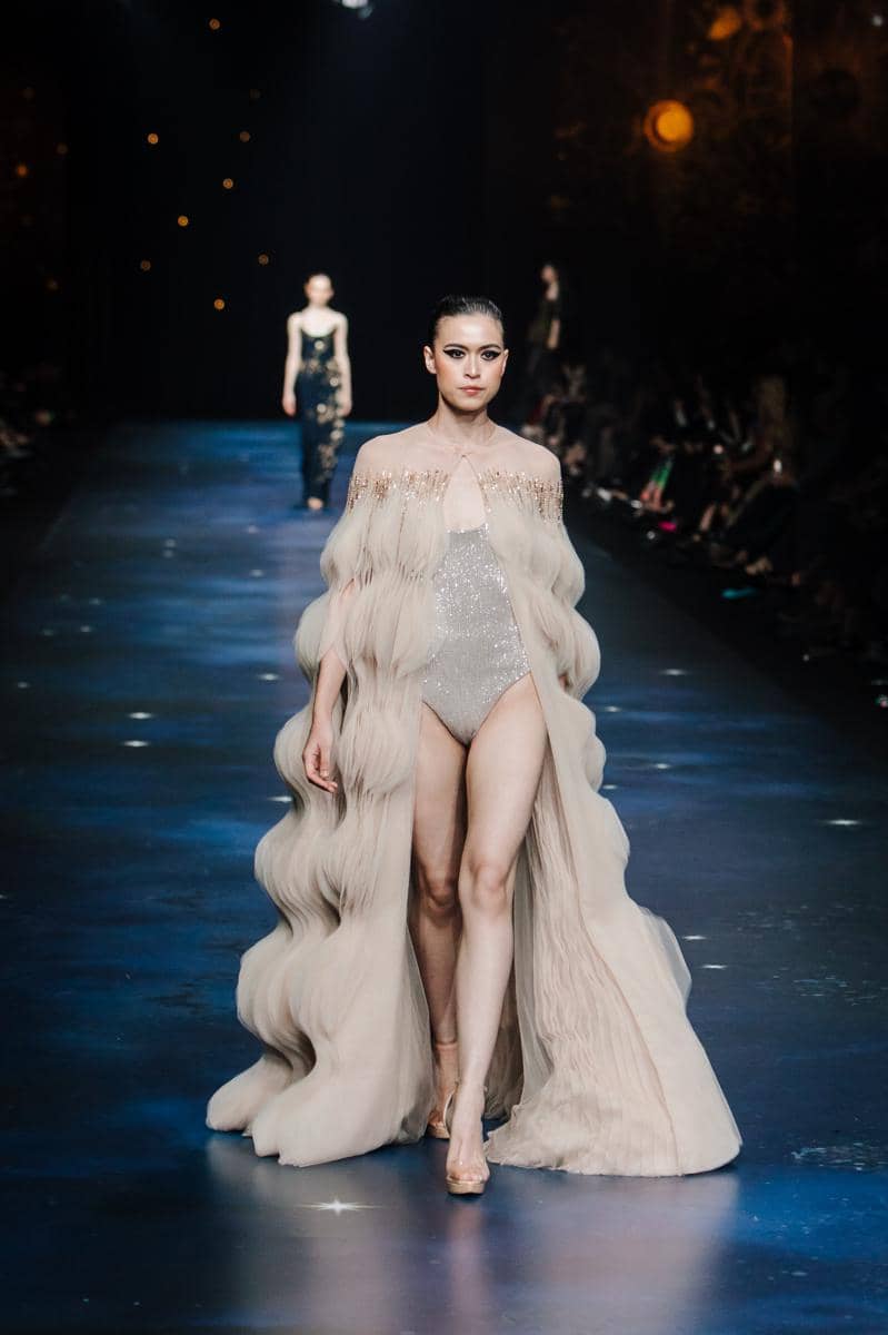 by @fawzypadly-3535.jpg, 1. Terdiri dari 77 set desain yang diciptakan lebih dari sekadar pakaian high-fashion, setiap rancangan adalah ode bagi keunikan setiap pribadi., 2. Koleksi 2025 “THE SIGN” merayakan keunikan tiap individu yang lahir dengan tanda pribadi yang tak akan pernah sama dengan orang lain., 3. Rentang warna menggunakan hitam, putih, biru tua, emas, perak, dan coral hadir dalam bahan lembut hingga tekstur jacquard, sifon, crepe, dan tulle, 4. Siluet kokoh arsitektural, solid, dengan pola eksperimental, ditata dengan permainan layer, dimensi dari transparansi, dan 3D dari aksen draping., 5. Aksen utama hadir lewat rasi bintang, galaksi misterius, dan sidik jari beads yang dirajut dengan detail ekstrem penuh savoir-faire.
