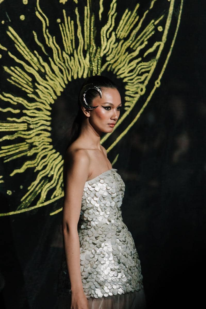 by @fawzypadly-2483.jpg, 1. Terdiri dari 77 set desain yang diciptakan lebih dari sekadar pakaian high-fashion, setiap rancangan adalah ode bagi keunikan setiap pribadi., 2. Koleksi 2025 “THE SIGN” merayakan keunikan tiap individu yang lahir dengan tanda pribadi yang tak akan pernah sama dengan orang lain., 3. Rentang warna menggunakan hitam, putih, biru tua, emas, perak, dan coral hadir dalam bahan lembut hingga tekstur jacquard, sifon, crepe, dan tulle, 4. Siluet kokoh arsitektural, solid, dengan pola eksperimental, ditata dengan permainan layer, dimensi dari transparansi, dan 3D dari aksen draping., 5. Aksen utama hadir lewat rasi bintang, galaksi misterius, dan sidik jari beads yang dirajut dengan detail ekstrem penuh savoir-faire.