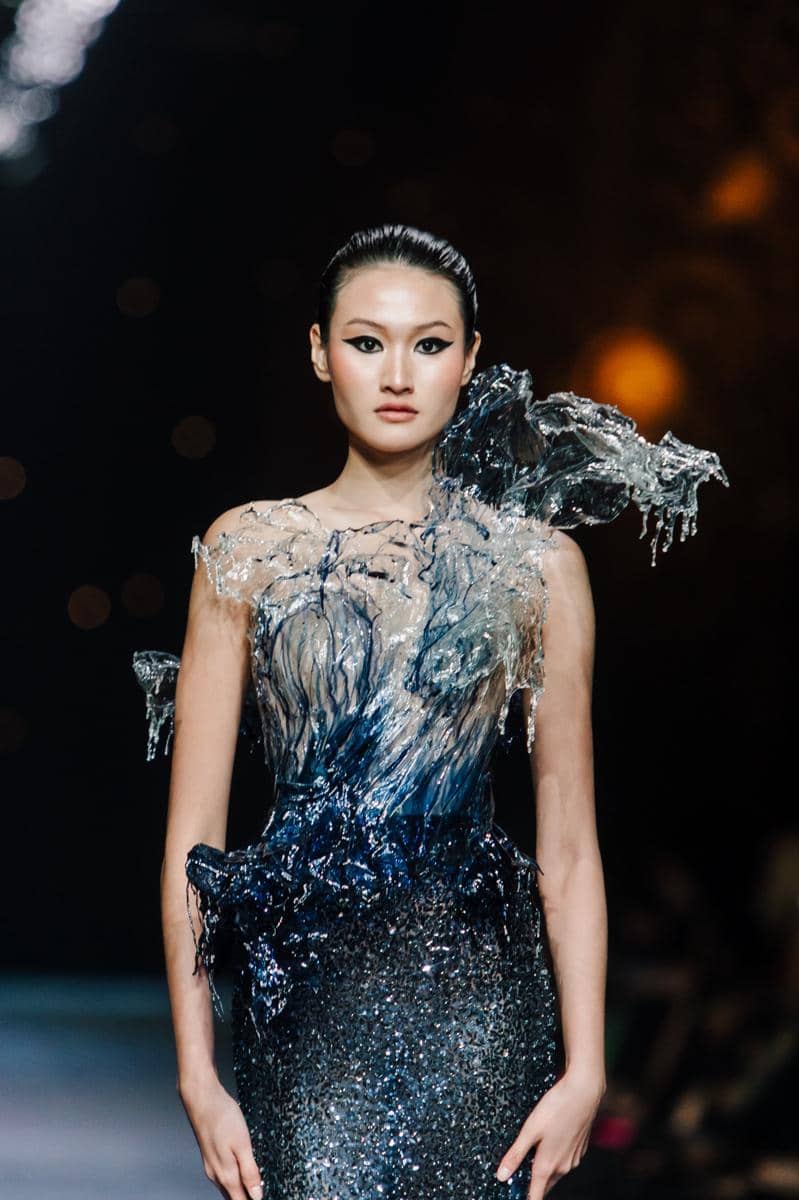 by @fawzypadly-3706.jpg, 1. Terdiri dari 77 set desain yang diciptakan lebih dari sekadar pakaian high-fashion, setiap rancangan adalah ode bagi keunikan setiap pribadi., 2. Koleksi 2025 “THE SIGN” merayakan keunikan tiap individu yang lahir dengan tanda pribadi yang tak akan pernah sama dengan orang lain., 3. Rentang warna menggunakan hitam, putih, biru tua, emas, perak, dan coral hadir dalam bahan lembut hingga tekstur jacquard, sifon, crepe, dan tulle, 4. Siluet kokoh arsitektural, solid, dengan pola eksperimental, ditata dengan permainan layer, dimensi dari transparansi, dan 3D dari aksen draping., 5. Aksen utama hadir lewat rasi bintang, galaksi misterius, dan sidik jari beads yang dirajut dengan detail ekstrem penuh savoir-faire.