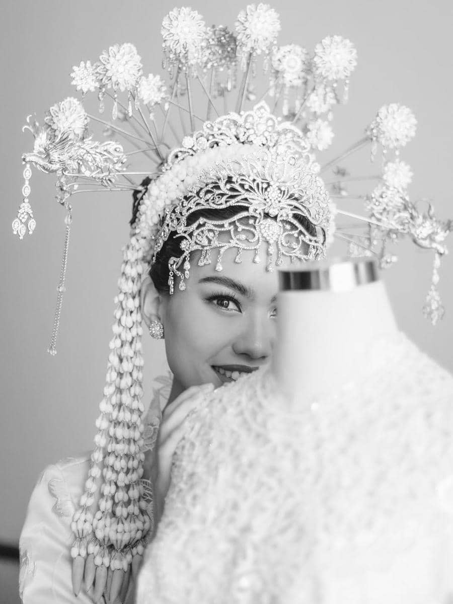 get (1).jpg, 1. Namira Adjani menggunakan kebaya putih dengan detail di bagian pinggul terinspirasi dari Kembang Kelapa yang menjadi ciri khas budaya Betawi., 2. Kembang Kelapa memiliki nilai filosofi sebagai lambang kemakmuran dan simbol kehidupan manusia yang bermanfaat, 3. Didiet Maulana juga memberikan aksen rumbai pada bagian dada yang membuat kebaya terlihat semakin menarik., 4. Namira Adjani menggunakan kain batik yang senasa dengan sang suami., 5. Sebagai sentuhan terakhir, Namira Adjani menggunakan headpiece lengkap dengan tusuk konde dan ronce melati