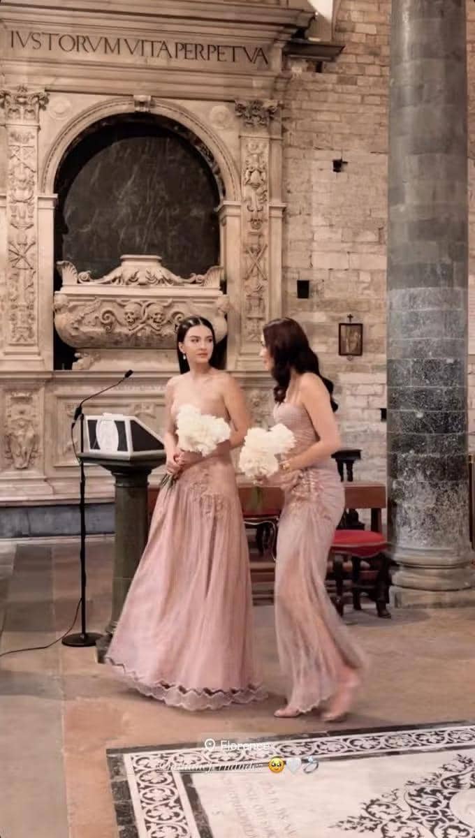 photo_2025-08-10-10_e2fcaa82-1403-4776-979d-7822651f77c9.jpg, 1. Raline Shah dan Luna Maya diundang menjadi bridesmaids di acara nikahan sang sahabat, Millane Fernandez, yang digelar di Florence, Italia. , 2. Banyak yang salfok dengan penampilan Raline saat hadir di acara pemberkatan pernikahan. Penampilannya elegan dengan gaun dusty pink yang serasi., 3. Gaun yang dipilih Raline Shah memiliki model strapless dengan bagian bawah rok berdetail lipit dengan material lace sebagai lapisan luarnya., 4. Rambut lurusnya ditata simple, digerai dengan tatanan sleek di bagian depan yang membuat keseluruhan penampilannya tetap minimalis namun elegan., 5. Bersama bridesmaid lain, ia juga terlihat mengenakan robe warna gold berbahan lace motif floral yang dipadukan dengan slip dress yang senada.