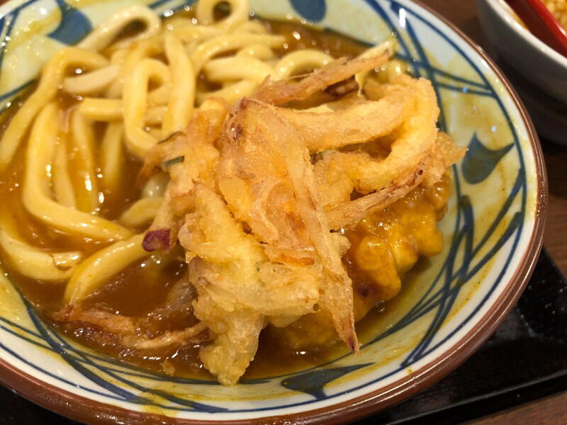 丸亀製麺の「カレーうどん」はたっぷりカレーが特徴, 丸亀製麺の「カレーうどん」は甘めのカレー。うどんに絡んでおいしい！ 口コミも紹介, 丸亀製麺の「カレーうどん」の値段・価格・コスパ, 丸亀製麺の「カレーうどん」の原材料・内容量・アレルギー情報, 丸亀製麺の「カレーうどん」のカロリー・栄養成分表示, 1.白ごはんでカレーライス, 2.人気No.1の天ぷら「かしわ天」を足す, 3.野菜かき揚げを足す, 4.半熟玉子天でカレーをまろやかに, 丸亀製麺の「カレーうどん」はテイクアウト（持ち帰り）できる？, 丸亀製麺の「トマたまカレーうどん」や「熱盛カレーうどん弁当」はいつまで？ 販売終了した？