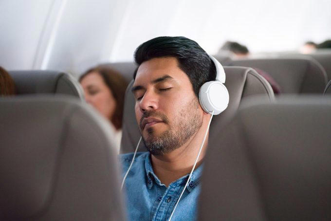 Book a window seat if you’re flying economy, Bring sleep accessories, especially if you have a middle seat, Take a power nap, Prioritize sleep before a long-haul flight, Limit your use of electronics, Skip the alcohol and caffeine, Bring a light-blocking eye mask, Stick to your bedtime routine, Opt out of the in-flight meal, Consider a sleep aid, About the experts, Why trust us