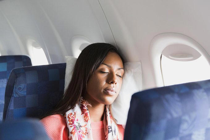 Book a window seat if you’re flying economy, Bring sleep accessories, especially if you have a middle seat, Take a power nap, Prioritize sleep before a long-haul flight, Limit your use of electronics, Skip the alcohol and caffeine, Bring a light-blocking eye mask, Stick to your bedtime routine, Opt out of the in-flight meal, Consider a sleep aid, About the experts, Why trust us
