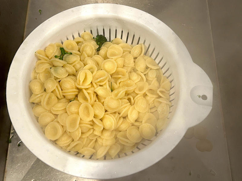 The show had to go on, so I drained the pasta and broccoli rabe in a colander. Ina Garten's orecchiette pasta features two types of sausage and broccoli rabe., First, I preheated the oven to 350 degrees Fahrenheit and prepped the sausages., After cooking the sausages for five minutes, I added the garlic., Then, it was time to add the tomatoes and wine.