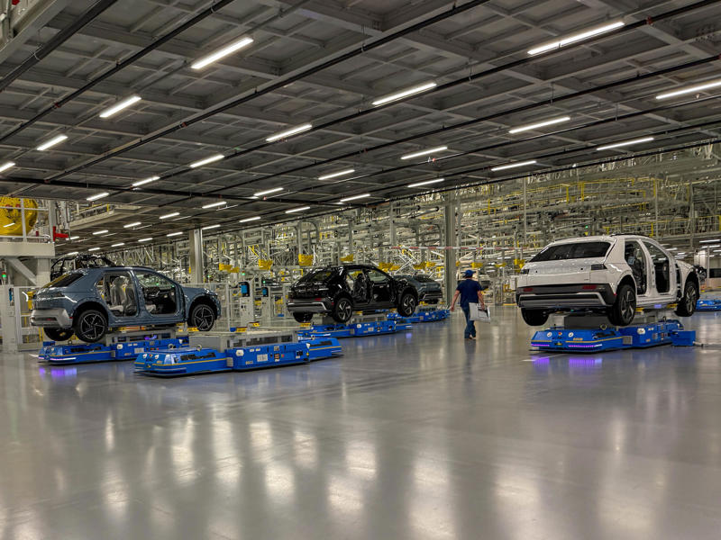 Partially assembled EVs are shuttled through from area to area by the automated robots. My tour began in the plant's modern main lobby., The Metaplant site consists of 11 buildings totalling 7.5 million square feet of space., Stamped parts are transported by automated guided vehicles, or AGVs., The stamped metal panels are then stored in these massive racks., Here are parts of the Ioniq 9, Hyundai's new flagship three-row EV SUV., The next part of the tour is the welding shop., The vehicles' interiors are then assembled by hand.
