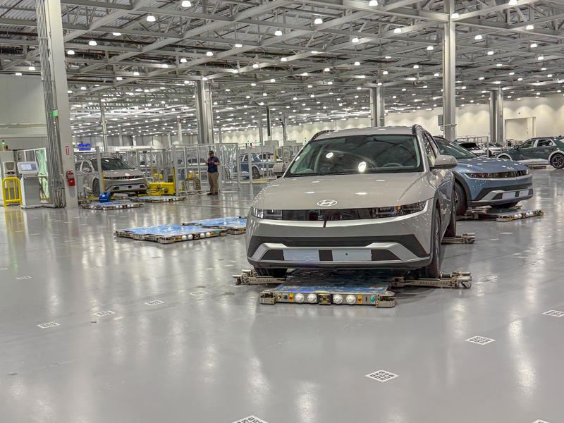 Assembled vehicles are loaded onto different AGVs that navigate the facility by reading the QR codes embedded into the floor. My tour began in the plant's modern main lobby., The Metaplant site consists of 11 buildings totalling 7.5 million square feet of space., Stamped parts are transported by automated guided vehicles, or AGVs., The stamped metal panels are then stored in these massive racks., Here are parts of the Ioniq 9, Hyundai's new flagship three-row EV SUV., The next part of the tour is the welding shop., The vehicles' interiors are then assembled by hand.