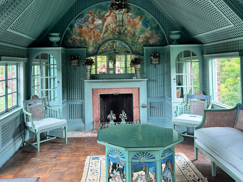 There are personalized touches all over the house's limestone exterior., It took three years to complete Coe Hall., One of the first rooms you can view is Coe's den., It's covered in dark wood, giving a masculine atmosphere., The art in the living room is original to the home., It's certainly not a bad place to spend your weekends., The craftsmanship throughout the house was impossible to miss., There was another portrait of Coe hanging in the corner., The main staircase felt straight out of a castle., And no, that's not wallpaper. This design was hand-painted onto the wall., The windows gave her a view of the gardens she painstakingly designed., This is her bathroom. Once again, it's very French., Now it was time to check out the much-revered grounds., Right off the bat, this fountain caught my eye., Can't you just hear someone saying, "Once upon a time…"?, Rogers entertained her friends in the Tea House on nice days., It looks like the inside of a Tiffany's box., Walking through it felt like walking through a storybook., One corner of the building was anchored by this giant palm tree., It has the largest collection of camellias under glass in the northeast., However, camellia season is in January, so we missed it.