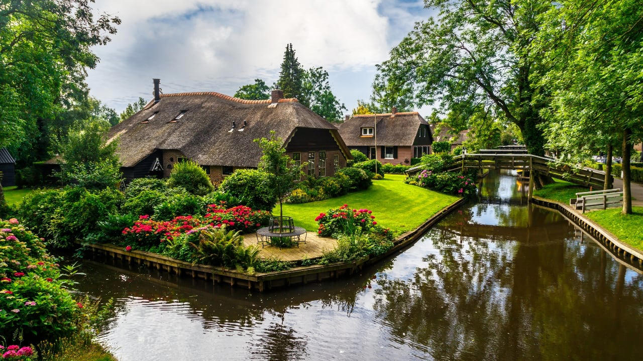 5. Giethoorn, Netherlands There are no cars in Giethoorn. Only boats, bridges, and hushed conversations. It is a village that floats, slowly, in its own rhythm. The canals speak softly; the thatched roofs never hurry. (Image: Canva) 1. Hallstatt, Austria Balanced between lake and limestone, Hallstatt reads like a forgotten chapter from an alpine fable. Its salt-stained history, mirrored waters, and slate-roofed homes draw quiet reverence, not crowds. In winter, it feels paused; in summer, painted. (Image: Canva), 2. Shirakawa-go, Japan Cradled by mountains and wrapped in thatch, Shirakawa-go holds firm to tradition. Its steep-roofed farmhouses, designed to endure snow and time, glow amber at dusk. The seasons arrive like guests—welcomed, noticed, remembered. (Image: Canva), 3. Colmar, France Colmar does not ask for attention—it commands it. With its riot of half-timbered homes, canal reflections, and Alsatian flourishes, it walks the line between theatre and truth. Even its shadows are deliberate. (Image: Canva), 4. Bibury, England Set beside the Coln and stitched into the hills, Bibury whispers of England before speed. Honey-coloured cottages in tight rows, trout streams that glisten without reason, and hedgerows that seem older than maps. (Image: Canva), 5. Giethoorn, Netherlands There are no cars in Giethoorn. Only boats, bridges, and hushed conversations. It is a village that floats, slowly, in its own rhythm. The canals speak softly; the thatched roofs never hurry. (Image: Canva), 6. Reine, Norway Beyond the Arctic Circle lies Reine—a scattering of crimson cabins that appear borrowed from a painting. Mountains rise like frozen waves behind them, and the sea never stops watching. Reine is remote, but never empty. (Image: Canva), 7. Eze, France High above the Riviera, where the cliffs fall into blue, sits Eze—a village of stone and shadow. Its alleys twist upward as if climbing toward memory. Time lingers here, in the scent of thyme and sea. (Image: Canva), 8. Goreme, Turkey Caves carved by wind and wonder—Goreme belongs to the Earth, not to man. Fairy chimneys pierce the sky, and hot-air balloons rise like thoughts at dawn. It is a village of both ground and sky. (Image: Canva), 9. Dinant, Belgium Hemmed in by cliff and river, Dinant feels composed rather than built. Saxophones hang from bridges, limestone watches from above, and the Meuse flows through it like a quiet refrain. Gothic never looked so lyrical. (Image: Canva), 10. Leavenworth, Washington, USA This village is not a replica—it’s a reinvention. Bavarian beams beneath American skies, brats beside apple pie. Surrounded by pine, performance, and peaks, Leavenworth is both celebration and curiosity, wrapped in wood and wonder. (Image: Canva)