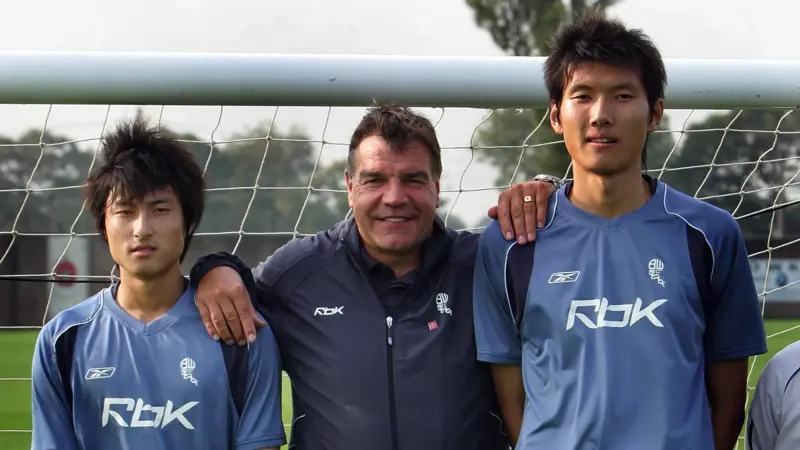 間違いなく、この中国人は史上最も背の高いサッカー選手一人だ。, 2019年に引退した同選手の身長は205センチ。, ヘディングが得意なスターストライカーだった。, その長身から、チームメイトから良くハイボールを受けていた。, もちろん、ヘディングで競り勝つのは難しい。, テクニックは劣ったが、長身のおかげで活躍。, この身長では機敏に動くことはできなかった。, 2006年にボルトンのセレクションを受けたが、残念ながら落選。, 2008年武漢でデビュー。, キャリア通算86試合に出場し、12ゴールをマークした。, 残念ながら、国際的な試合でインパクトを与えることはできなかった。