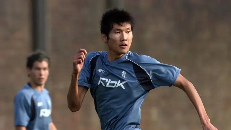 間違いなく、この中国人は史上最も背の高いサッカー選手一人だ。, 2019年に引退した同選手の身長は205センチ。, ヘディングが得意なスターストライカーだった。, その長身から、チームメイトから良くハイボールを受けていた。, もちろん、ヘディングで競り勝つのは難しい。, テクニックは劣ったが、長身のおかげで活躍。, この身長では機敏に動くことはできなかった。, 2006年にボルトンのセレクションを受けたが、残念ながら落選。, 2008年武漢でデビュー。, キャリア通算86試合に出場し、12ゴールをマークした。, 残念ながら、国際的な試合でインパクトを与えることはできなかった。