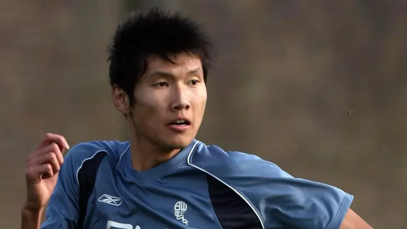 間違いなく、この中国人は史上最も背の高いサッカー選手一人だ。, 2019年に引退した同選手の身長は205センチ。, ヘディングが得意なスターストライカーだった。, その長身から、チームメイトから良くハイボールを受けていた。, もちろん、ヘディングで競り勝つのは難しい。, テクニックは劣ったが、長身のおかげで活躍。, この身長では機敏に動くことはできなかった。, 2006年にボルトンのセレクションを受けたが、残念ながら落選。, 2008年武漢でデビュー。, キャリア通算86試合に出場し、12ゴールをマークした。, 残念ながら、国際的な試合でインパクトを与えることはできなかった。
