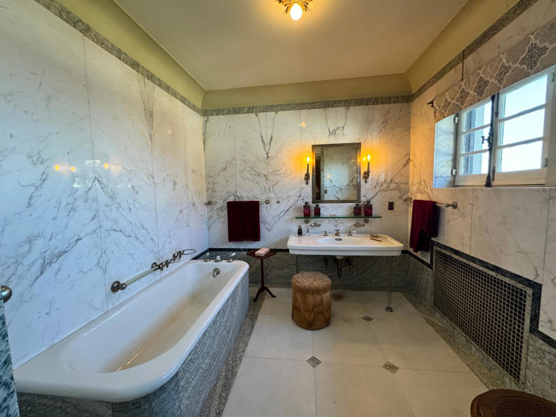 Here's one of the guest bathrooms at Eagle's Nest. Note the marbled walls and tub. Inside the grounds are hiking trails, gardens, and a gift shop., Before I toured the home, I visited the museum grounds., But the landscaping was still immaculate., Then it was time to head over to Eagle's Nest., One side of the mansion is a natural history museum., The first room I saw was the dining room., The ceiling is constructed from Florida cedar, or Southern Red cedar., This is her changing room and bathroom., The house was set on a hill, so the yard was multi-level., First, I walked to the right., There was a large reflecting pool., But the main attraction was, once again, the view., To my surprise, it was a filled-in saltwater pool., They'd even left the ladder in., There were also changing rooms.