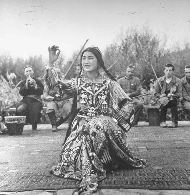 24. 35. "Lili'uokalani, the overthrown final monarch of the Hawaiian Kingdom, sitting on the porch of her private residence with her dog Poni, 1917", 33. "Jewish Children with their Teacher in Samarkand. Early color photograph from Russia, created by Sergei Mikhailovich Prokudin-Gorskii as part of his work to document the Russian Empire from 1909 to 1915", 31. "Aboriginal boy and puppy. Australia, 1914. Photo by Frank Hurley", 30. "An Arab Christian Girl from Bethlehem. 1923", 29. "Watusi Man in Ruanda (now Rwanda) in the 1920s", 27. "An Abyssinian (Ethiopian) warrior, carrying a rifle and shield and wearing a lion’s mane headdress, at the coronation ceremonies of Emperor Haileselassie, 1930", 25. "Peruvian woman with her baby in the Andes, 1930s-1940s", 24. "A Uighur dancer performing to music. Xinjiang, 1943. Photo taken by William Vandivert", 23. "Radna Ayusheev, an ethnic Bashkir apart of the 63rd Soviet Naval Infantry Brigade, 1944", 22. "Pakistani swimmers Sultan Karim Ali (L) and Anwar Aziz Chaudhry (R) at the Empire Pool in Wembley, London, during the 1948 Summer Olympics (United Kingdom 1948)", 20. "A Japanese Geisha wearing a kimono and sitting with her Samisen, a traditional string instrument - 1950", 18. "Korean children at the Malli-dong neighbourhood, in Seoul, South Korea - 1959", 17. "Dancing in Ghana — 1961/2", 16. "A Kurdish peshmerga with his family in Iraqi Kurdistan. 1965", 15. "Children from Gorkha, Nepal during 1970", 14. "Nils Johan Mienna, a boy belonging to the Sami people, poses for the camera in his traditional costume. Norway, 1977, By Erik Borg for the National Geographic", 12. "Khmer Rouge child soldiers with M16 rifles, Galaw, Cambodia (1979)", 11. "Afghan Girl, 1984", 10. "East-Timorese women photographed during the Indonesian occupation of East-Timor, 1984", 9. "San woman in Namibia listening to some tunes (1984)", 8. "Turkmen boys wear traditional traditional Telpek hats, (1980s), Turkmen SSR", 5. "Cakchiquel people of Patzutzun, Guatemala, 1993. Photographed by John Isaac", 4. "A Chechen veteran fighting as a volunteer during the First Chechen War, 1994"