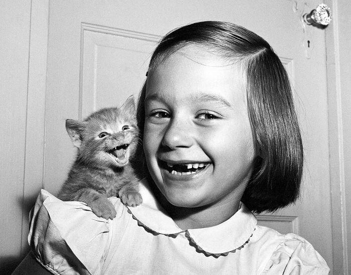 A Shared Moment: Paula and Her Kitten Royal Dining with Angela Lansbury and Basil Rathbone, Breaking Barriers: Mary Wallace’s Historic Drive, Strength and Heritage in Canyon De Chelly, Portrait of Youth: Kiowa Girl, Berber Beauty: Ouled Nail Girl, A Shared Moment: Paula and Her Kitten, Marilyn Monroe’s Playful Potato Sack Look, Challenging the Rules: Brooklyn Dress Code Protest, 1940, Wolof Family Portrait by Emile Noal, Reunion After a Long Voyage, Elegance in Motion: Manon Chaufour by Martin Imboden, Dad’s Got Moves: Melbourne, 1940s, Fire Escape Embrace, 1946, Ani Chokyi of Tibet, Captured in Darjeeling, 1890s, Headlines and Daydreams, Champs Elysées, 1947, Timeless Athens: The Acropolis in 1860, Catharina ‘Toto’ Koopman: A Parisian Muse, 1933, On the Road Together: Family Hitchhiking, California, Einstein and His Beloved Violin, 1941, Edmund Kesting’s Play with Light and Shadow, 1930, Champagne Inspector in Protective Mask, Helen Bennett’s Stunning Spider Dress, 1939, Harriet Hoctor’s Graceful Question Mark, 1925, Double the Dazzle: The Dolly Sisters in the 1920s, Glamour at The Forbidden City, 1948, Double the Glamour: Mother-Daughter Style, 1954, Cardboard Couture: Sicilian Suit Substitute, The Day Daddy Came Home: Hector Murdoch’s Return, Courage Behind Bars: Mexico, 1935, Milk Time Mischief at Arch Badertscher’s Farm