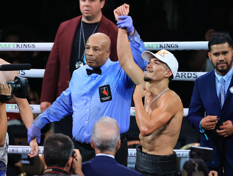 Referee Allen Huggins holds up the arm of Brandon Figueroa after his unanimous-decision victory over Joet Gonzalez in their featherweight bout.