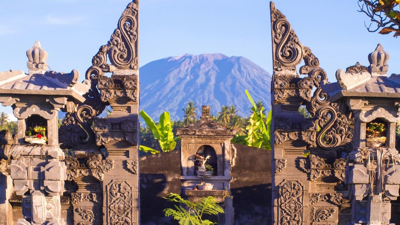 4. Amed: A Diver’s Hideaway with a Laid-Back Vibe Amed’s coastline is worlds apart from Seminyak’s glitz. With its volcanic black-sand beaches, traditional jukung boats bobbing in the water, and easy access to coral reefs and WWII shipwrecks, it’s a paradise for snorkelers and divers. The pace is slow, the people warm, and the sunsets unforgettable. Don’t miss: Sunrise views of Mount Agung and a day trip to the Japanese shipwreck in Lipah Beach. (Image: Canva) 1. Sidemen Valley: The Soul of Rural Bali Located in East Bali, Sidemen is a lush valley that feels like a time capsule. The region is framed by Mt. Agung, Bali’s sacred volcano, and layered with stunning rice terraces, bamboo forests, and sleepy villages. Hike through the fields, visit traditional weaving centers, or simply relax in a bamboo hut overlooking a river. It’s a favorite among yogis, writers, and slow travelers looking to escape the buzz of Ubud. Why go: Serene landscapes, fewer tourists, great base for cultural immersion and eco-friendly stays. (Image: Canva), 2. Nyang Nyang Beach: Bali’s Untamed Coastline One of the last untouched beaches in South Bali, Nyang Nyang demands effort—around 500 steps down a cliff—but rewards you with solitude, turquoise waves, and dramatic limestone backdrops. You won’t find sunbeds or bars here—just driftwood, wildflowers, and your own patch of sand. Tip: Go early in the morning to avoid the heat and enjoy the beach in silence. (Image: Canva), 3. Sangeh Monkey Forest: Tranquility Amidst Sacred Trees Tucked away in Badung Regency, Sangeh Monkey Forest is older and quieter than its more famous cousin in Ubud. The forest is home to towering nutmeg trees, Balinese temples, and a well-behaved tribe of macaques known for their less aggressive nature. It’s perfect for a quiet cultural detour. Insider fact: Locals believe the trees in the forest are sacred and spiritually protected. (Image: Canva), 4. Amed: A Diver’s Hideaway with a Laid-Back Vibe Amed’s coastline is worlds apart from Seminyak’s glitz. With its volcanic black-sand beaches, traditional jukung boats bobbing in the water, and easy access to coral reefs and WWII shipwrecks, it’s a paradise for snorkelers and divers. The pace is slow, the people warm, and the sunsets unforgettable. Don’t miss: Sunrise views of Mount Agung and a day trip to the Japanese shipwreck in Lipah Beach. (Image: Canva), 5. Munduk: Bali’s Misty Mountain Escape Set high in Bali’s northern highlands, Munduk is a tranquil village surrounded by coffee plantations, waterfalls, and dense forests. Cooler temperatures and misty mornings create a refreshing contrast to the island’s coast, inviting visitors to explore hiking trails and traditional villages far from the tourist bustle. Why it’s special: A peaceful retreat for nature lovers and trekkers seeking unspoiled landscapes and authentic local culture. (Image: Canva), 6. Penglipuran Village: Tradition Preserved in Harmony This Balinese Hindu village near Bangli is renowned for its commitment to preserving traditional architecture and customs. The village layout is based on the Tri Mandala concept—spatial zoning rooted in Balinese cosmology. It’s meticulously clean, with manicured gardens and bamboo forests at its edge. Why visit: Witness authentic Balinese culture and community-driven sustainability in action. (Image: Canva), 7. Banyu Wana Amertha Waterfall: A Hidden Natural Wonder Tucked away in the lush hills of Buleleng, this collection of waterfalls is lesser-known but absolutely spectacular. Multiple falls cascade through the jungle, offering secluded swimming spots and stunning photo opportunities. A short trek through flower farms and coffee plantations adds charm to the journey. Pro tip: Wear water shoes and bring a picnic for a truly immersive nature escape. (Image: Canva), 8. Menjangan Island: Bali’s Best Snorkeling Without the Crowds Situated in West Bali National Park, Menjangan Island is part of a protected marine reserve. The water clarity is exceptional, with vibrant coral walls, reef fish, and occasional sightings of reef sharks or turtles. On land, the island is home to wild deer that roam freely. Good to know: Access is by boat from Labuan Lalang; guided snorkel or dive trips can be arranged locally. (Image: Canva), 9. Pura Beji Sangsit: A Hidden Temple of Intricate Carvings Located in the village of Sangsit in North Bali, Pura Beji is a serene temple famed for its elaborate stone carvings and unique architectural style. Unlike the bustling temples near Ubud, it offers a peaceful atmosphere where visitors can appreciate Bali’s rich artistic heritage in quiet contemplation. What makes it unique: The temple’s detailed decorations and tranquil setting provide a glimpse into traditional Balinese craftsmanship away from tourist crowds. (Image: Canva)