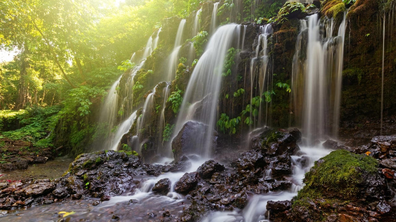 7. Banyu Wana Amertha Waterfall: A Hidden Natural Wonder Tucked away in the lush hills of Buleleng, this collection of waterfalls is lesser-known but absolutely spectacular. Multiple falls cascade through the jungle, offering secluded swimming spots and stunning photo opportunities. A short trek through flower farms and coffee plantations adds charm to the journey. Pro tip: Wear water shoes and bring a picnic for a truly immersive nature escape. (Image: Canva) 1. Sidemen Valley: The Soul of Rural Bali Located in East Bali, Sidemen is a lush valley that feels like a time capsule. The region is framed by Mt. Agung, Bali’s sacred volcano, and layered with stunning rice terraces, bamboo forests, and sleepy villages. Hike through the fields, visit traditional weaving centers, or simply relax in a bamboo hut overlooking a river. It’s a favorite among yogis, writers, and slow travelers looking to escape the buzz of Ubud. Why go: Serene landscapes, fewer tourists, great base for cultural immersion and eco-friendly stays. (Image: Canva), 2. Nyang Nyang Beach: Bali’s Untamed Coastline One of the last untouched beaches in South Bali, Nyang Nyang demands effort—around 500 steps down a cliff—but rewards you with solitude, turquoise waves, and dramatic limestone backdrops. You won’t find sunbeds or bars here—just driftwood, wildflowers, and your own patch of sand. Tip: Go early in the morning to avoid the heat and enjoy the beach in silence. (Image: Canva), 3. Sangeh Monkey Forest: Tranquility Amidst Sacred Trees Tucked away in Badung Regency, Sangeh Monkey Forest is older and quieter than its more famous cousin in Ubud. The forest is home to towering nutmeg trees, Balinese temples, and a well-behaved tribe of macaques known for their less aggressive nature. It’s perfect for a quiet cultural detour. Insider fact: Locals believe the trees in the forest are sacred and spiritually protected. (Image: Canva), 4. Amed: A Diver’s Hideaway with a Laid-Back Vibe Amed’s coastline is worlds apart from Seminyak’s glitz. With its volcanic black-sand beaches, traditional jukung boats bobbing in the water, and easy access to coral reefs and WWII shipwrecks, it’s a paradise for snorkelers and divers. The pace is slow, the people warm, and the sunsets unforgettable. Don’t miss: Sunrise views of Mount Agung and a day trip to the Japanese shipwreck in Lipah Beach. (Image: Canva), 5. Munduk: Bali’s Misty Mountain Escape Set high in Bali’s northern highlands, Munduk is a tranquil village surrounded by coffee plantations, waterfalls, and dense forests. Cooler temperatures and misty mornings create a refreshing contrast to the island’s coast, inviting visitors to explore hiking trails and traditional villages far from the tourist bustle. Why it’s special: A peaceful retreat for nature lovers and trekkers seeking unspoiled landscapes and authentic local culture. (Image: Canva), 6. Penglipuran Village: Tradition Preserved in Harmony This Balinese Hindu village near Bangli is renowned for its commitment to preserving traditional architecture and customs. The village layout is based on the Tri Mandala concept—spatial zoning rooted in Balinese cosmology. It’s meticulously clean, with manicured gardens and bamboo forests at its edge. Why visit: Witness authentic Balinese culture and community-driven sustainability in action. (Image: Canva), 7. Banyu Wana Amertha Waterfall: A Hidden Natural Wonder Tucked away in the lush hills of Buleleng, this collection of waterfalls is lesser-known but absolutely spectacular. Multiple falls cascade through the jungle, offering secluded swimming spots and stunning photo opportunities. A short trek through flower farms and coffee plantations adds charm to the journey. Pro tip: Wear water shoes and bring a picnic for a truly immersive nature escape. (Image: Canva), 8. Menjangan Island: Bali’s Best Snorkeling Without the Crowds Situated in West Bali National Park, Menjangan Island is part of a protected marine reserve. The water clarity is exceptional, with vibrant coral walls, reef fish, and occasional sightings of reef sharks or turtles. On land, the island is home to wild deer that roam freely. Good to know: Access is by boat from Labuan Lalang; guided snorkel or dive trips can be arranged locally. (Image: Canva), 9. Pura Beji Sangsit: A Hidden Temple of Intricate Carvings Located in the village of Sangsit in North Bali, Pura Beji is a serene temple famed for its elaborate stone carvings and unique architectural style. Unlike the bustling temples near Ubud, it offers a peaceful atmosphere where visitors can appreciate Bali’s rich artistic heritage in quiet contemplation. What makes it unique: The temple’s detailed decorations and tranquil setting provide a glimpse into traditional Balinese craftsmanship away from tourist crowds. (Image: Canva)
