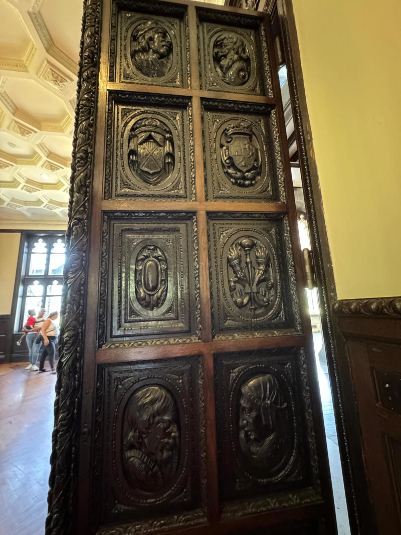 These doors, which were originally carved in Spain in the 16th century, lead to the billiards room. It also features the largest fireplace in the home., The billiards room also has a luxurious window seat., Directly next to the breakfast room was another wood-paneled study., It has yet another perfect window seat., It's also one of the only rooms with a private bathroom., We stopped at one more guest room, which was more modest., As the tour concluded, we were able to explore the gardens outside.