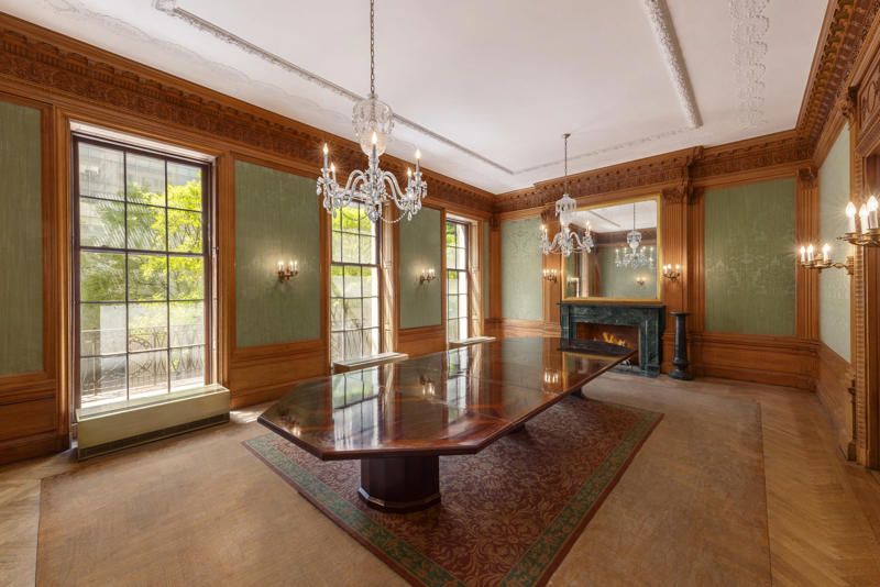 Rooms on the upper floors feature floor-to-ceiling windows and Juliet balconies. The five-story townhouse is located across from the Museum of Modern Art., The entry gallery on the first floor features wood paneling throughout., Neo-Georgian architectural touches include columns and decorative molding known as cornices., Two staircases lead to the upper floors., Rooms on the upper floors feature floor-to-ceiling windows and Juliet balconies., The dining room is shaped like an octagon.
