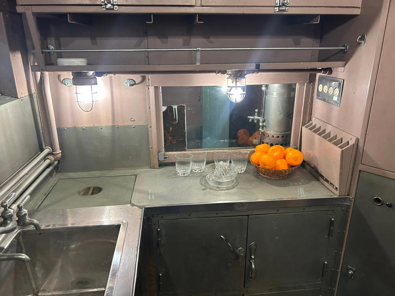 On the other side of the kitchen, the staff had pantry space to plate the dishes. To carry the president, the unique armored car had enhanced security features., In the kitchen, an onboard chef had access to ovens and refrigerators., The car housed two staff members: a chef and a porter., The car included two guest bedrooms along with a presidential suite., The presidential suite included the president's sleeping area., The first lady's room was located parallel to the president's., A narrow hallway led from the staterooms to the observation deck., The observation lounge featured some of the presidential car's original furniture., During the refurbishment, a submarine escape hatch was added to the car.