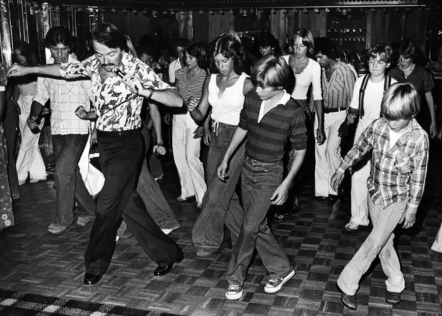 13. In 1978, Disco Dancing Lessons Spread to Suburbs Like Beaverton, Oregon 1. Waiting In Line to See Star Wars, 1977, 2. January 19th 1977, The One and Only Day it Snowed in Miami, 3. Disco Sally, a 78-Year-Old Studio 54 Regular, Becomes a Symbol of the Era in 1978, 4. A Businessman Lights a Cigarette Inside a New York City Phone Booth in 1980, 5. Two Women Sit Casually on a Fire Escape in Harlem, NYC, in 1978, 6. Harrison Ford Appears as Colonel G. Lucas in Apocalypse Now, 1979, 7. In 1978, a Toddler Poses Next to the Family's New Color TV Like It's a Family Member, 8. Salesmen Sit on the Hoods of New Cars Waiting for Buyers at a California Dealership in 1979, 9. Kids Jump From a Fire Escape Onto Mattresses in NYC's Lower East Side, 1979, 10. Comic-Con San Diego in 1980 Captures the Wild Beginnings of Pop Culture Fandom, 11. The World's Largest Disco Draws Crowds to Buffalo in 1978, 12. Young Roller Skater in Red Moves Through Midtown Manhattan, 1979, 13. In 1978, Disco Dancing Lessons Spread to Suburbs Like Beaverton, Oregon, 14. An Apple II Computer and a Young Steve Jobs Revolutionize Tech in 1977, 15. A Woman Leans in to Kiss a Windsor Guard in a Whimsical Moment, 1980, 16. Two Guys Play Atari in Their Living Room in 1978, Defining Home Entertainment, 17. National Space Invaders Championship in 1980 Showcases a New Era of Gamers, 18. A Local News Crew in Texas Interviews Parents After Taking Kids to See Alien, 1979, 19. Young Woman in a "Consenting Adult" Shirt Enjoys the Rolling Stones in 1978, 20. In 1979, Reflections on the Dance Floor Captured the Disco Craze From Above, 21. A Canadian Gas Station Refuses to Fuel Soviet Ladas to Protest the Invasion of Afghanistan, 1980, 22. Subway Riders Carry Lawn Chairs for a Beach Day in NYC, Summer 1978, 23. High School Seniors Pose Before Heading on a Ski Trip in 1980, 24. Young Girl Embraces Teddy Boy Fashion and Rock 'n' Roll Dancing, 1979, 25. In 1980, Bronx Teens Turn the Streets Into a Stage With BMX Tricks, 26. Olivia Newton-John and John Travolta Redefine Teen Style on the Set of Grease, 1978, 27. KISS Fans in Buffalo, NY, Fully Embrace Glam Rock Culture, 1978, 28. New UK Prime Minister Margaret Thatcher Celebrates Her Election Victory, 1979, 29. The Sony Walkman Hits the Market With a Bold Ad Declaring "There's a Revolution in the Streets", 1980, 30. A Young Man Spins the Top Hits of 1978 on AM Radio Studio, 31. Four New Jersey Teens Check Under the Hood of a Car With a Backwards Design, 1979, 32. Elvis Presley's Final Performance in 1977 Leaves Fans With an Iconic Farewell, 33. Protesters Flood the Capitol in March 1980 to Oppose Military Draft Registration, 34. Staten Island Families Resort to Kerosene Lamps During the 1977 Blackout